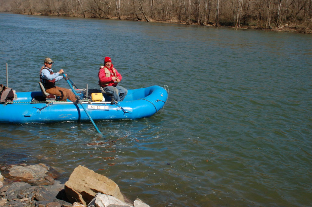 Isang imahe ng dalawang lalaki sa isang asul na balsa na nangingisda malapit sa isang malalim na mabatong pool