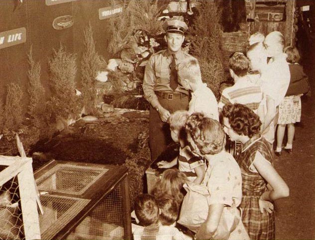 Isang itim at puting imahe ng isang game warden na nakikipag-usap sa mga bata