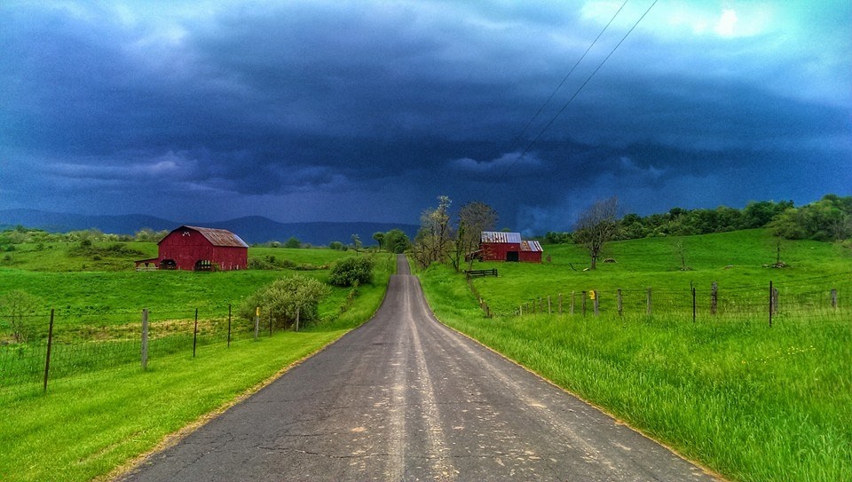 Isang larawan ng isang country road na may mga kamalig na nakikita sa background