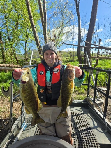 Mangingisda sa isang bangka na may hawak na dalawang smallmouth bass mula sa Clinch River.