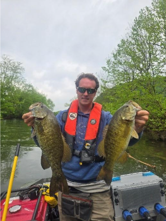 Mangingisda sa isang bangka na may hawak na dalawang smallmouth bass mula sa North Fork Holston River.
