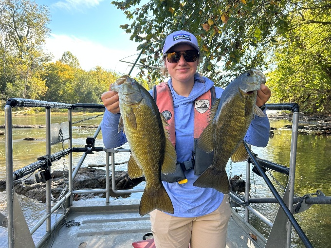 Mangingisda sa isang bangka na may hawak na dalawang isdang bass sa South Fork Shenandoah River.