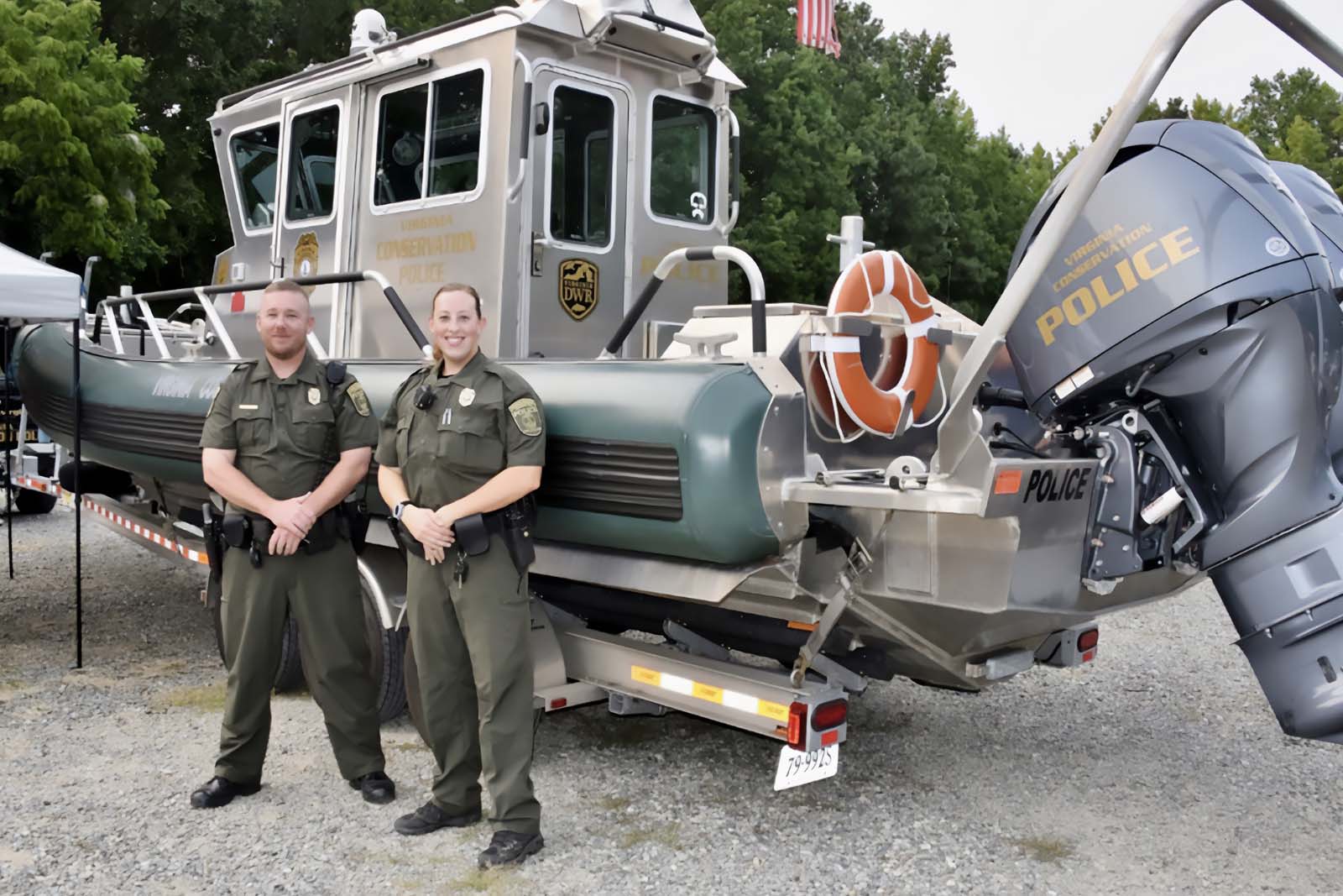 Nakatayo ang mga CPO sa harap ng bangka ng pulis sa isang trailer