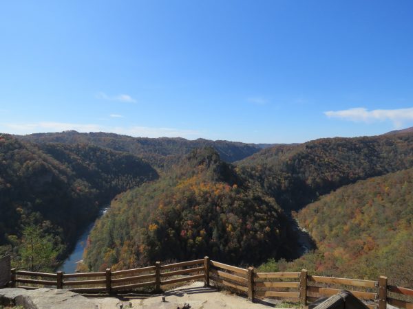 Isang imahe ng isang overlook sa interstate park ng Break, mayroon itong magandang taglagas na bulubundukin na may ilog na dumadaloy sa ibabang kaliwang sulok at isang hadlang ng mga bakod na gawa sa kahoy sa ibabaw ng isang bato sa harapan.