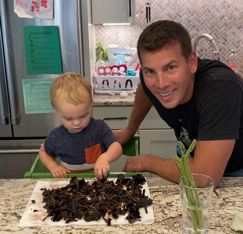 Isang imahe ng isang batang lalaki sa tabi ng isang tumpok ng mga kabute at ang kanyang ama