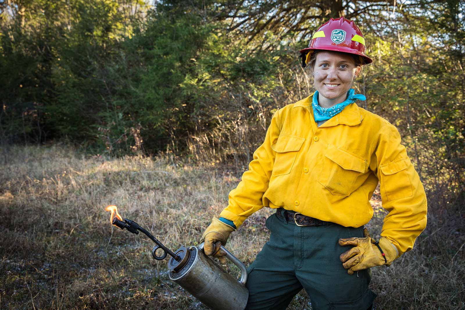 Nagpose ang isang fire crew na may drip torch.