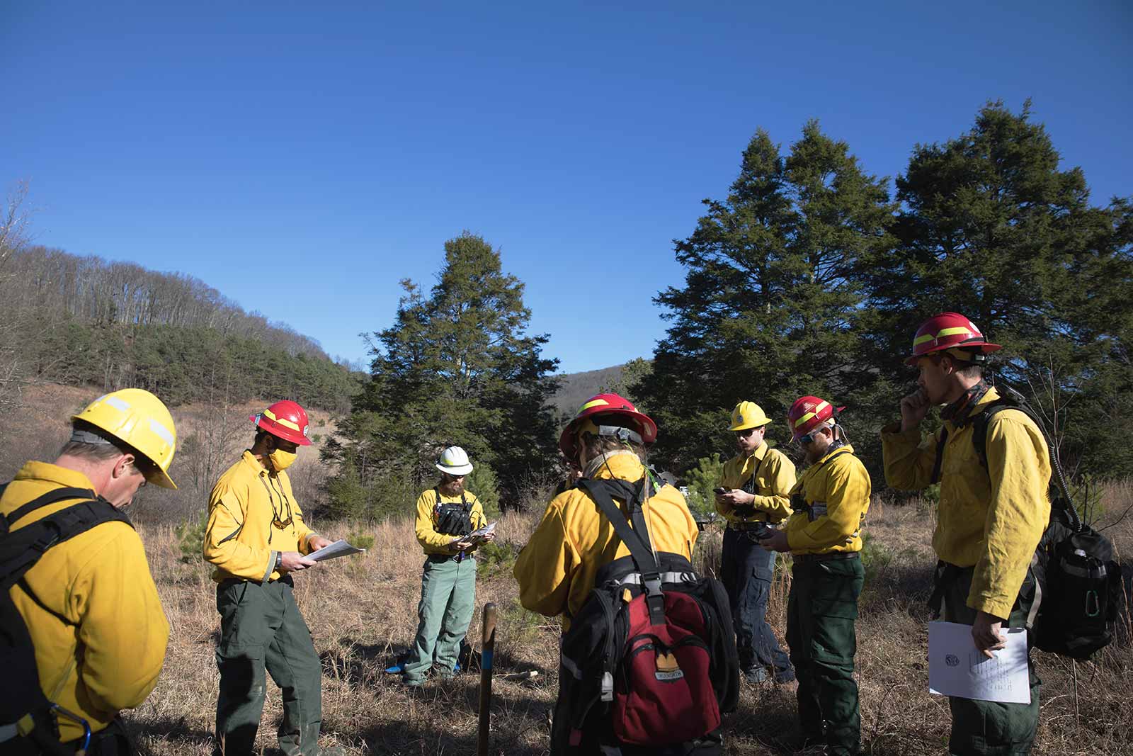 Nagpupulong ang isang crew ng bumbero upang suriin ang iniresetang plano ng paso para sa araw.