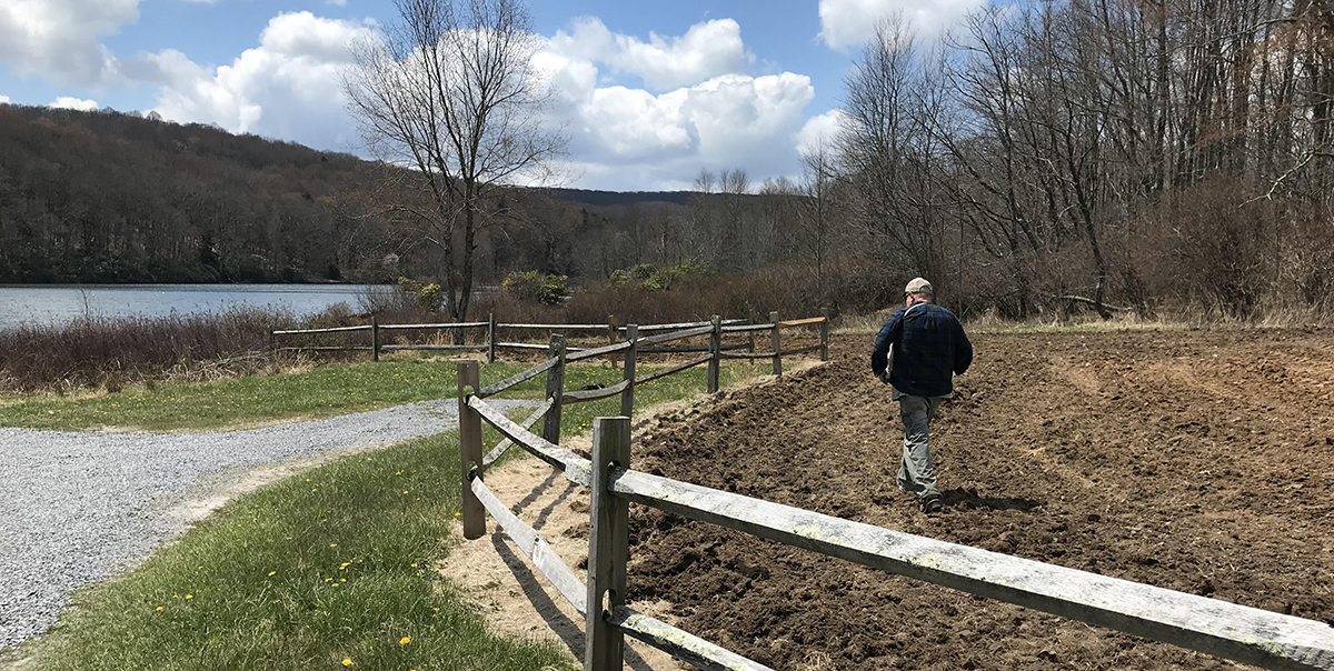 Isang kawani ng DWR na namamahagi ng pataba at binhi sa disked na lupa.