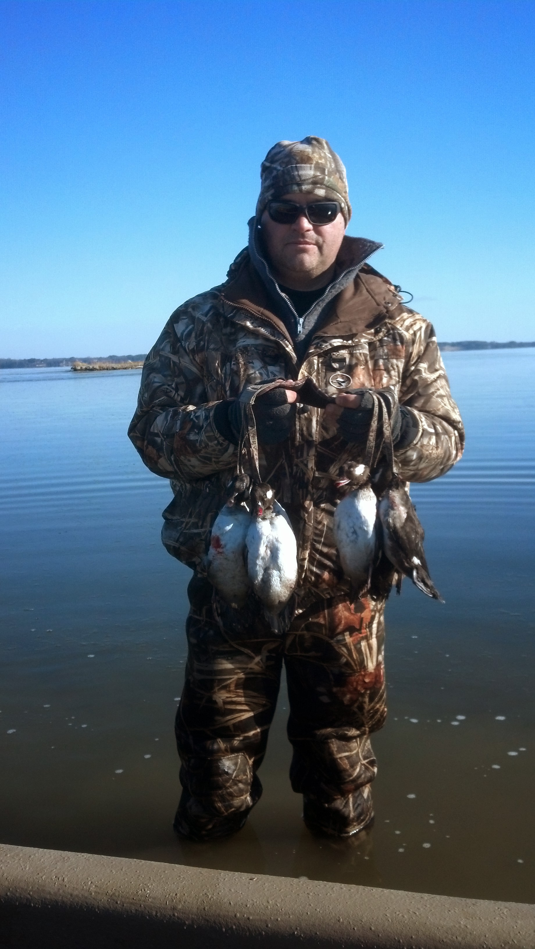 Isang imahe ng isang lalaki sa nagyeyelong tubig na may hawak na isang grupo ng mga patay na itik