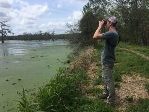 Isang taong may binocular na nakatingin sa labas ng lawa