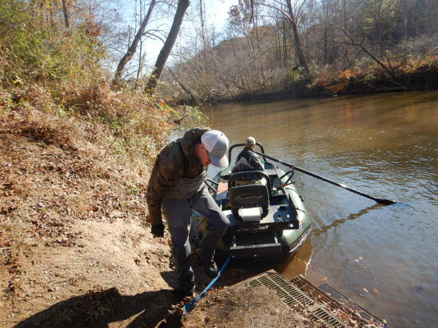 Ang berdeng electrofishing raft ay na-undock mula sa lupa kasama ang dalawang empleyado