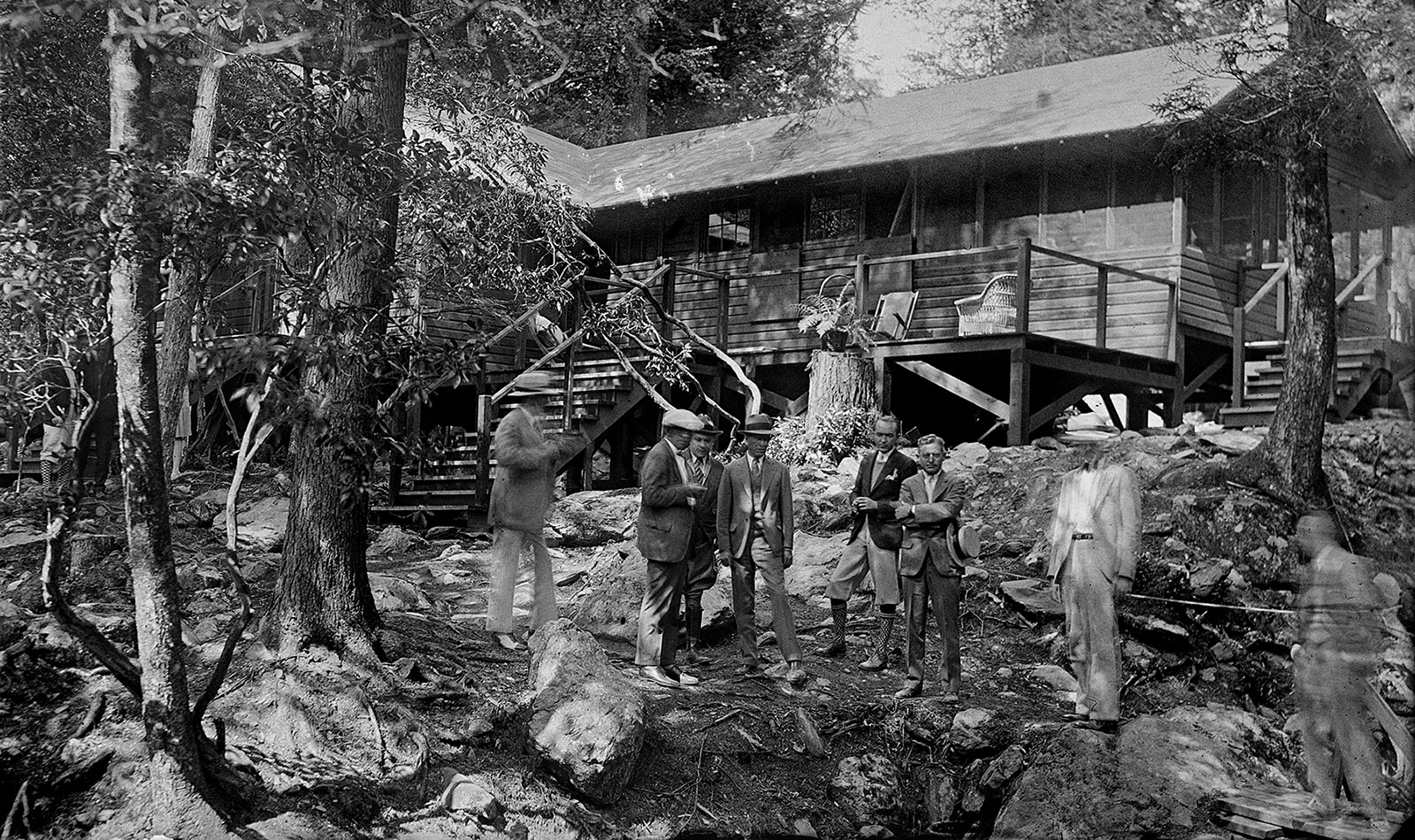Isang black-and-white na larawan ng isang grupo ng mga tao na nakasuot ng 1930s-era na pananamit na nakatayo sa harap ng The Brown House, isang kahoy na tirahan na itinayo sa overlooking ng Rapidan River.