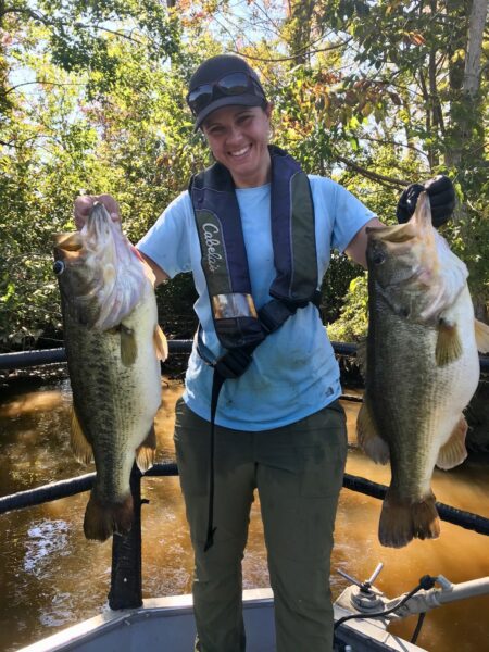 Pinuno ng Tidal Rivers Project na si Margi Whitmore na may dalawang malaking Largemouth Bass.