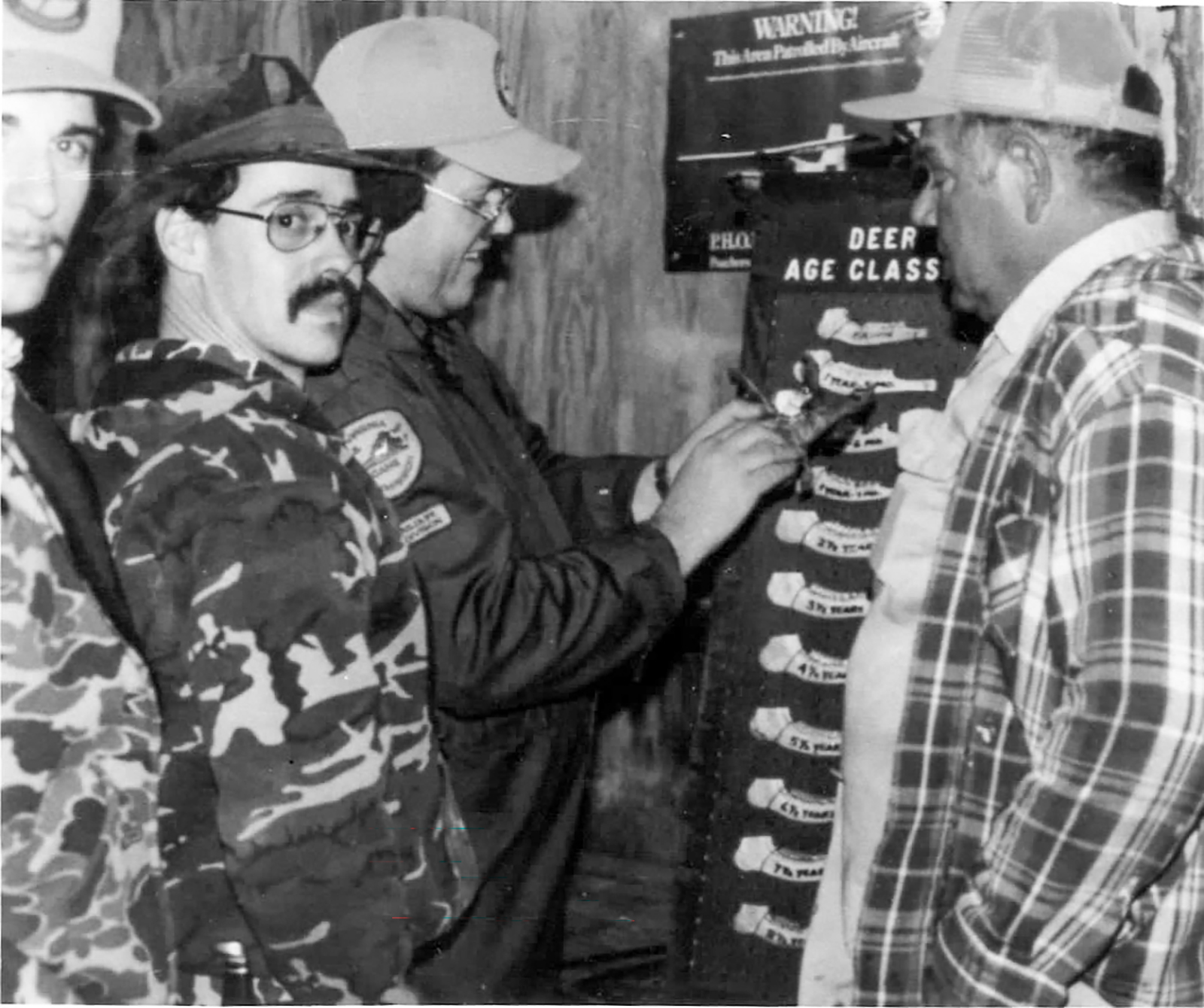 Isang lumang black-and-white na imahe na nagpapakita ng mga mangangaso na sumusukat sa mga buto ng panga ng usa.