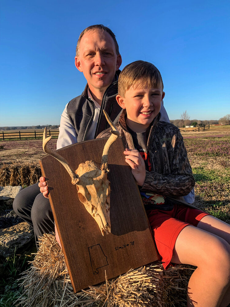 Isang imahe ng isang lalaki at ang kanyang araw na may hawak na isang naka-frame na bungo ng usa na siyang unang usa na kanilang binaril nang magkasama