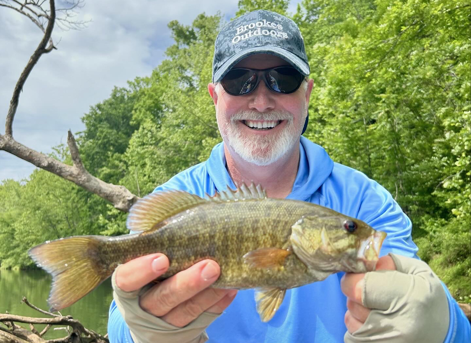 Isang lalaking may hawak na smallmouth bass fish para sa isang larawan.