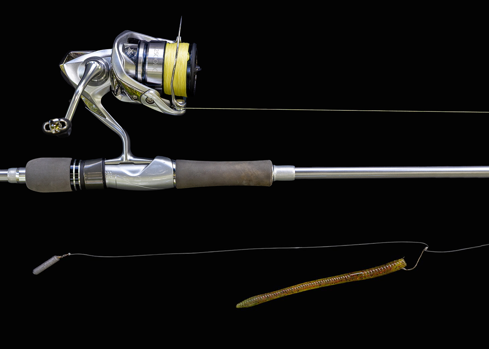 Isang close-up na larawan ng isang fishing rod at reel na may mahabang plastic na uod na nakakabit sa isang kawil.