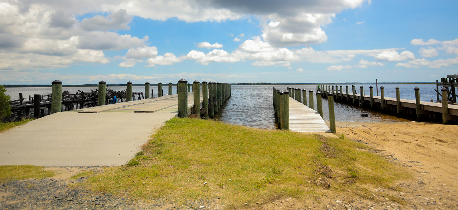 Isang larawan ng isang rampa ng bangka sa kanan at isang pantalan sa kaliwa na umaabot sa tubig.