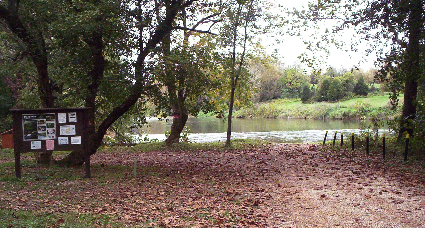 Isang larawan ng isang lawa na humahantong sa isang DWR boating access site na may kahoy na notice board sa harapan