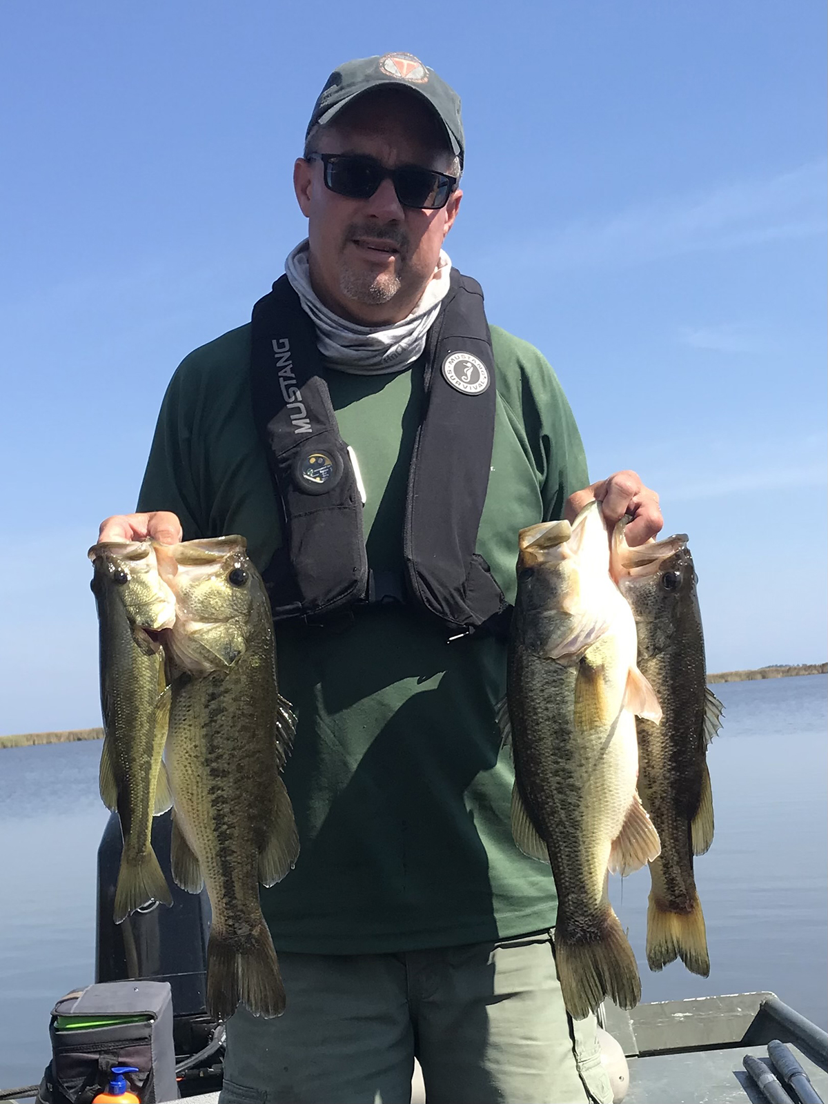 Isang lalaki, si Chad Boyce, na may hawak na apat na largemouth bass habang nakatayo sa isang bangkang pangisda. Nakasuot siya ng berdeng pang-itaas na may lifejacket , salaming pang-araw at baseball cap.