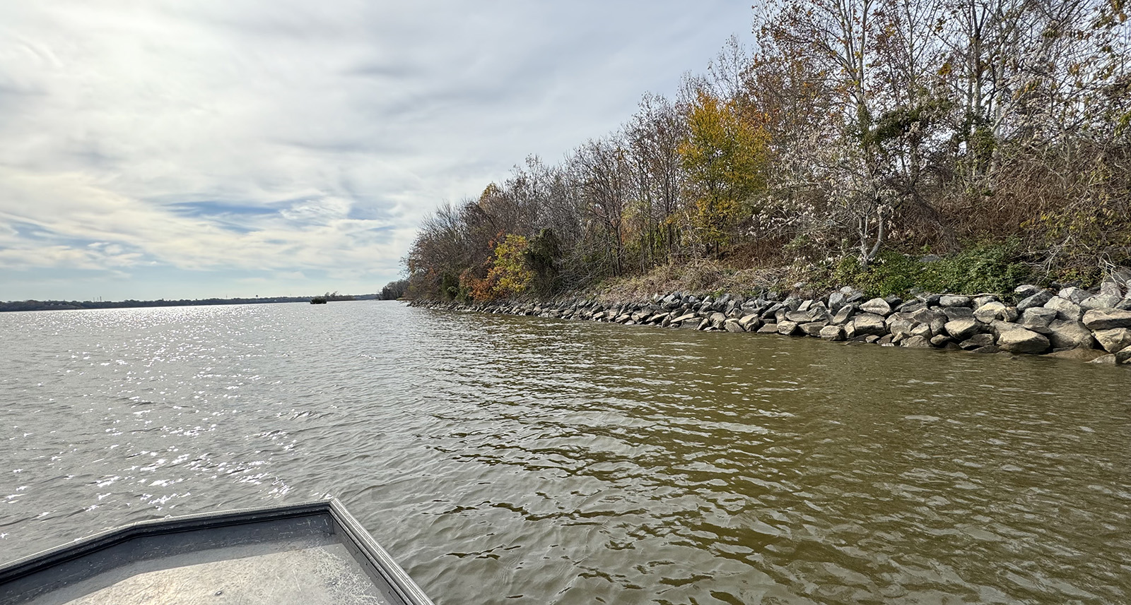 Isang larawan na kinunan mula sa isang maliit na bangka ng isang baybayin ng ilog na may linya ng malalaking bato, na kilala bilang rip-rap.