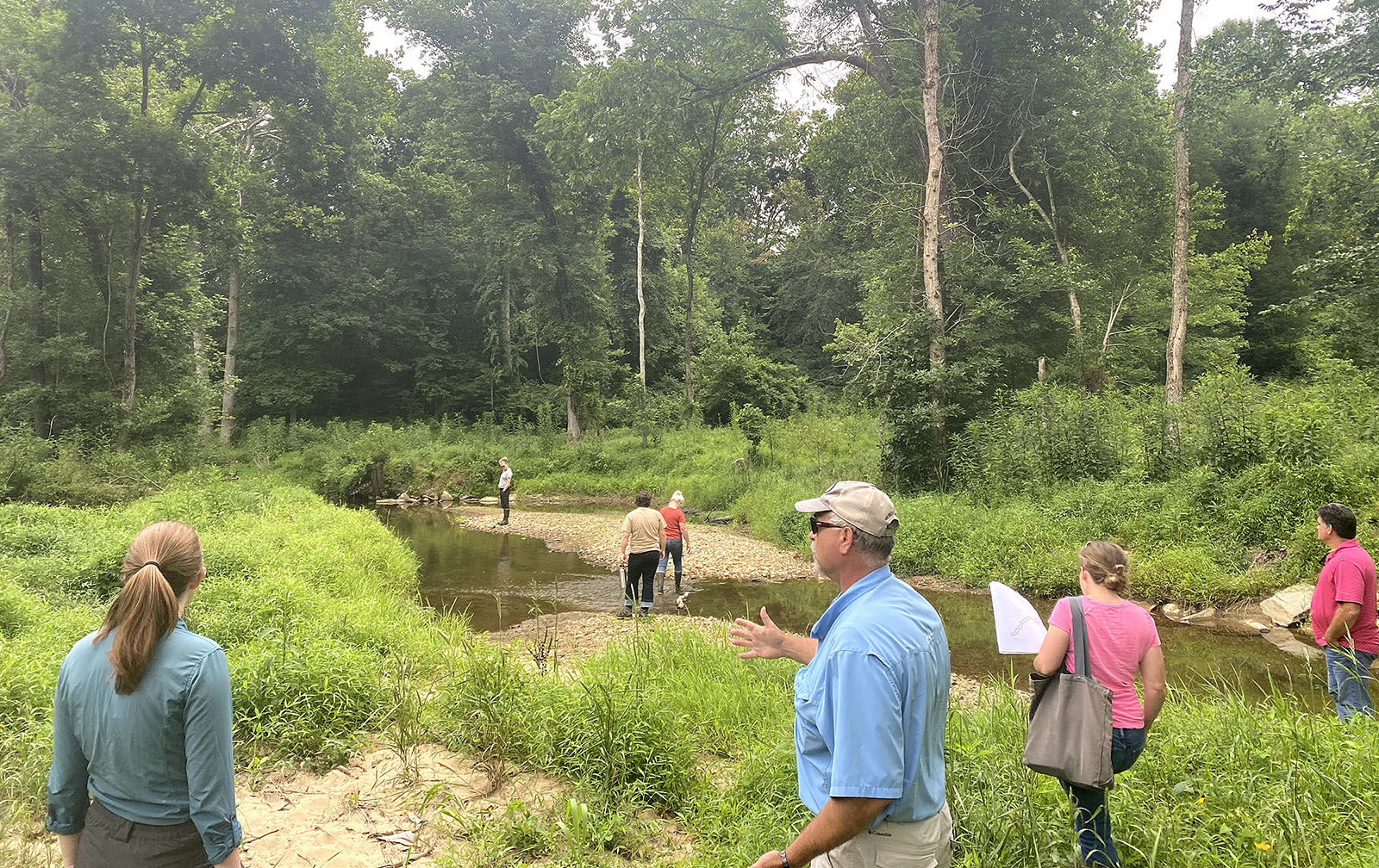 Isang grupo ng mga tao ang nagtitipon sa pampang ng isang batis, sa talakayan.