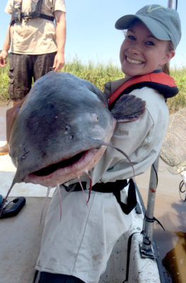 Isang batang babae na may hawak na malaking asul na hito